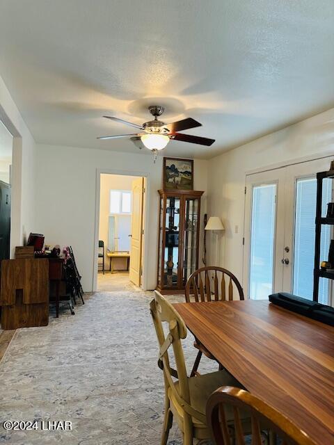 dining area with ceiling fan, french doors, and a textured ceiling