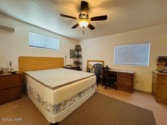 carpeted bedroom featuring ceiling fan, a wall mounted air conditioner, and electric panel