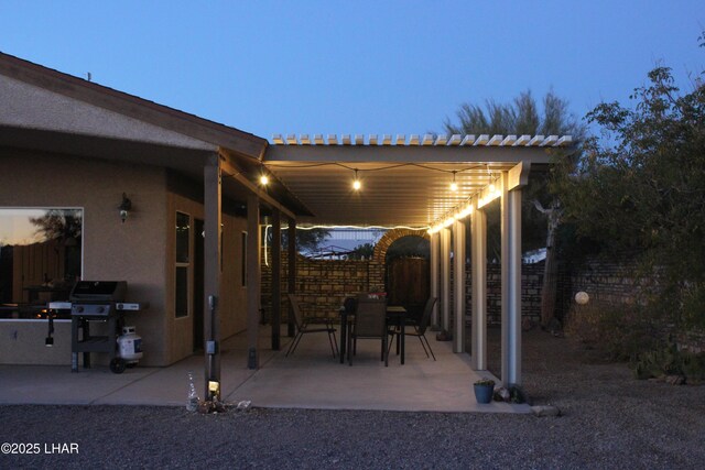 patio terrace at dusk featuring fence and area for grilling