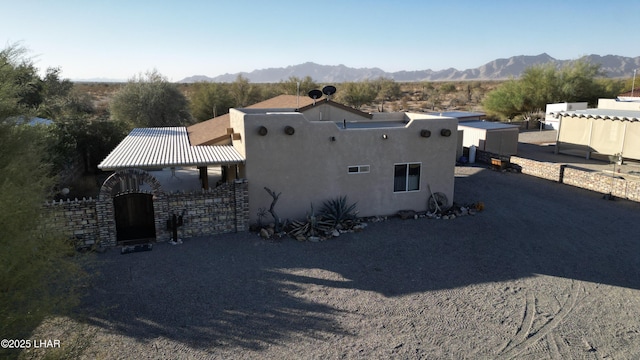 view of home's exterior featuring a gate, a mountain view, fence, and stucco siding