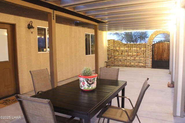 view of patio featuring outdoor dining area and a gate