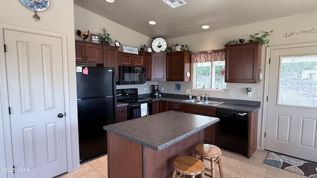 kitchen with dark countertops, a sink, a kitchen island, and black appliances