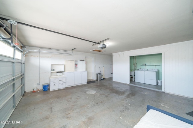 garage with washing machine and dryer and a garage door opener