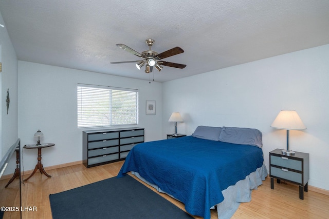 bedroom featuring hardwood / wood-style flooring, ceiling fan, and a textured ceiling