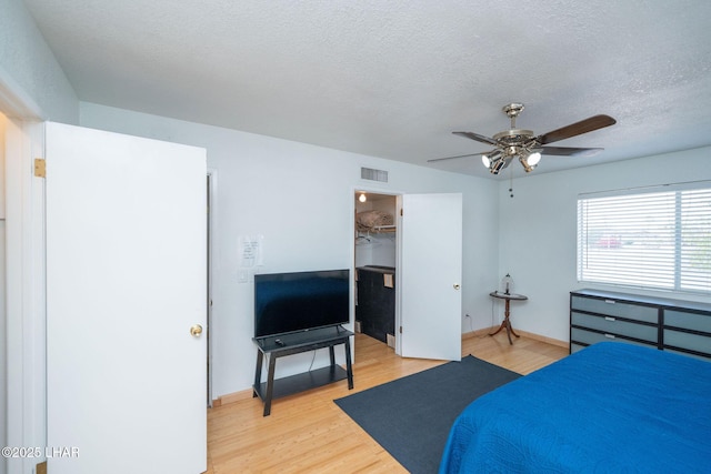 bedroom with hardwood / wood-style flooring, ceiling fan, a spacious closet, and a textured ceiling