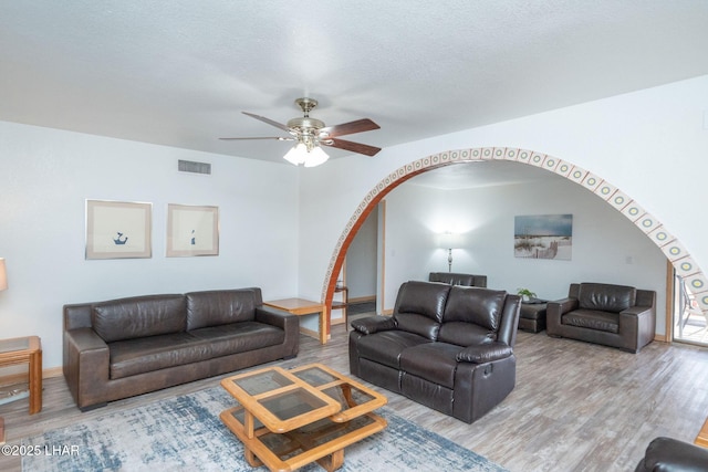 living room featuring ceiling fan, wood-type flooring, and a textured ceiling