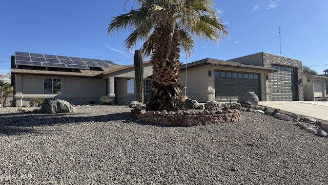 ranch-style house with a garage and solar panels