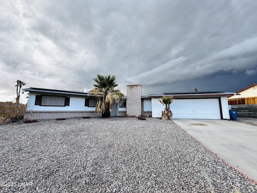 ranch-style home featuring a garage, brick siding, concrete driveway, and fence