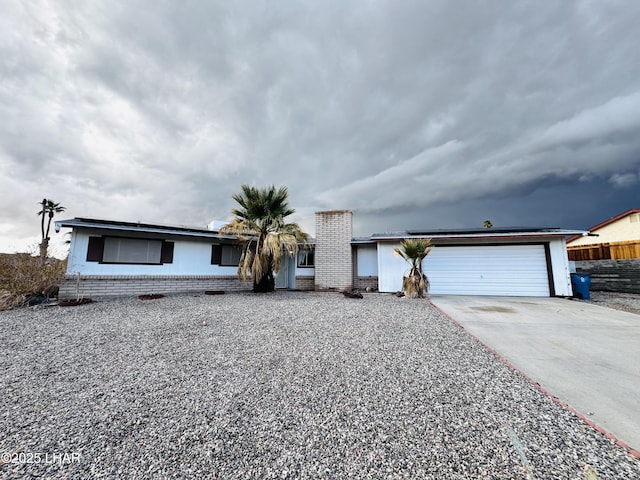 ranch-style home featuring a garage, brick siding, concrete driveway, and fence