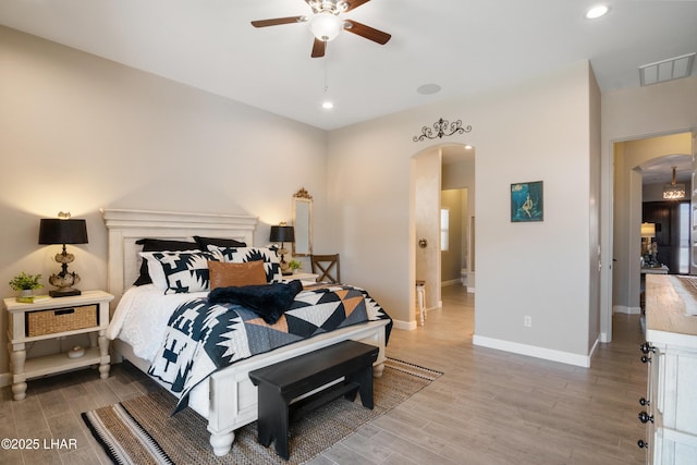 bedroom with visible vents, baseboards, arched walkways, and wood finished floors