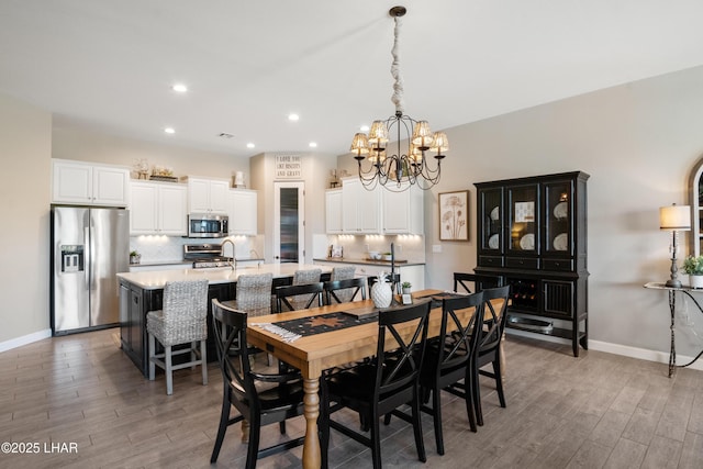 dining space with baseboards, recessed lighting, a chandelier, and light wood-style floors