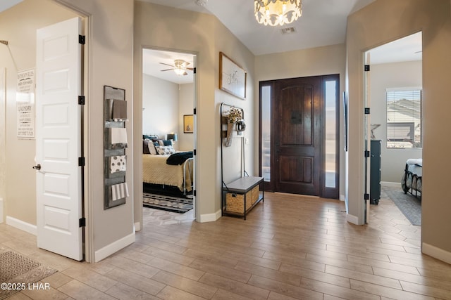 foyer with light wood finished floors, baseboards, and visible vents