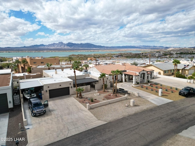 exterior space with stucco siding, concrete driveway, an attached garage, a water and mountain view, and a residential view