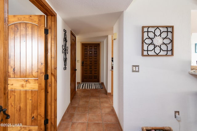 corridor with light tile patterned floors and a textured ceiling