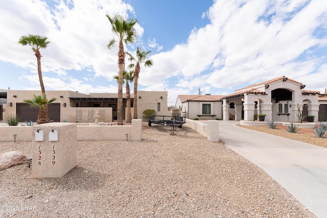 view of front of home featuring a fenced front yard, a tile roof, and stucco siding