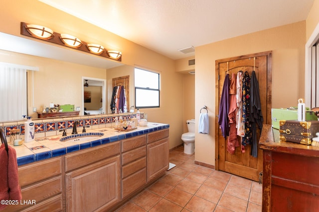 full bath featuring toilet, a sink, visible vents, tile patterned floors, and double vanity