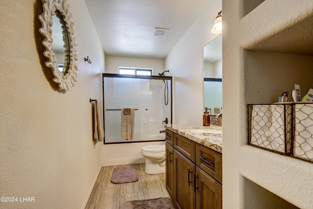 full bathroom with toilet, vanity, bath / shower combo with glass door, and a textured ceiling