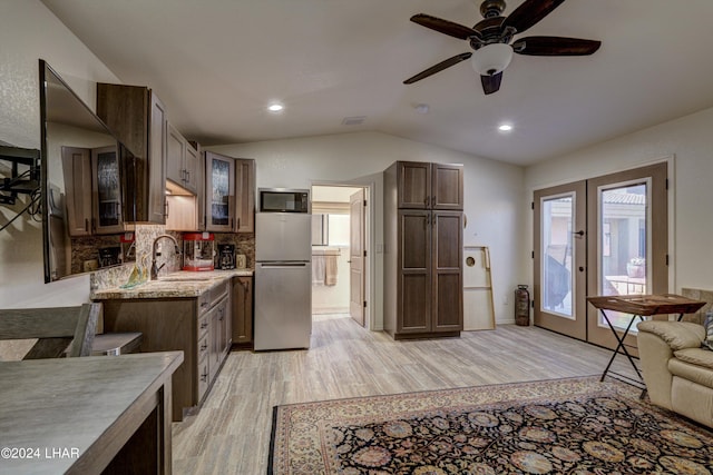 kitchen with lofted ceiling, sink, stainless steel refrigerator, and light wood-type flooring