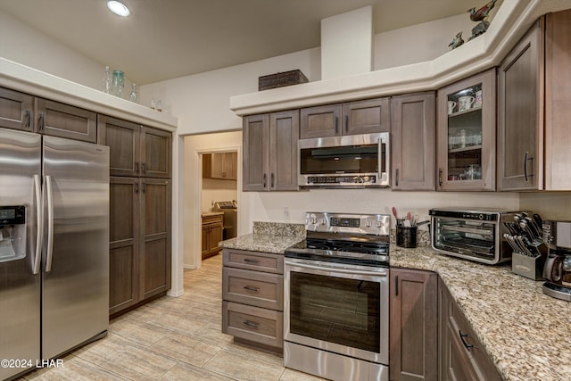 kitchen featuring light stone counters, dark brown cabinetry, and appliances with stainless steel finishes