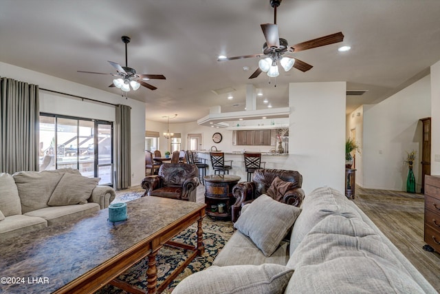 living room with lofted ceiling, ceiling fan with notable chandelier, and wood-type flooring