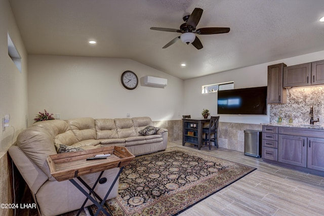 living room with an AC wall unit, lofted ceiling, sink, ceiling fan, and light hardwood / wood-style floors