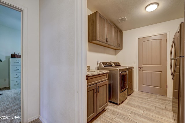 laundry area with cabinets, separate washer and dryer, and a textured ceiling