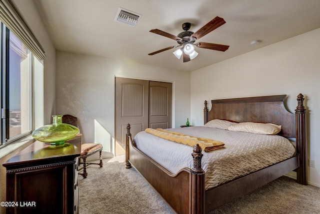 bedroom with ceiling fan, a closet, and light carpet