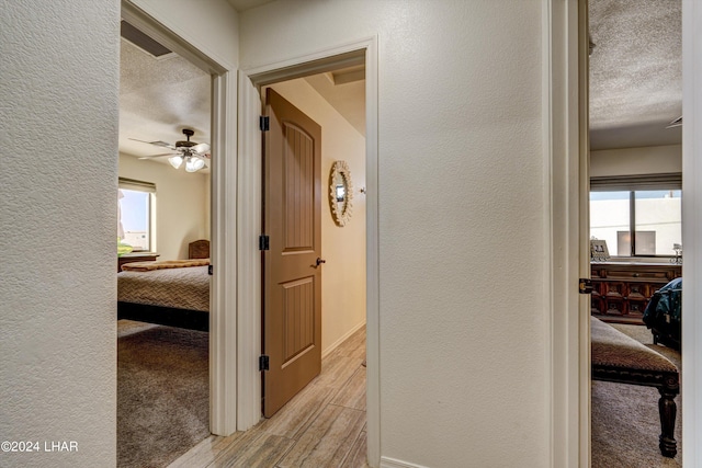 hallway featuring a textured ceiling and light wood-type flooring