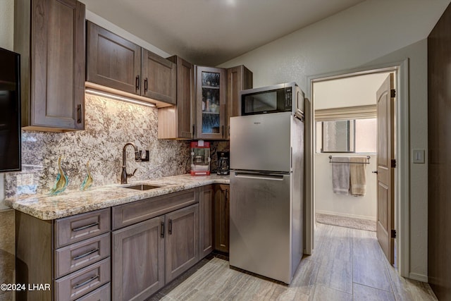 kitchen featuring tasteful backsplash, appliances with stainless steel finishes, sink, and light stone counters