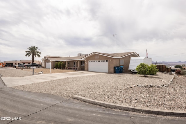 ranch-style home featuring concrete driveway, stucco siding, and an attached garage