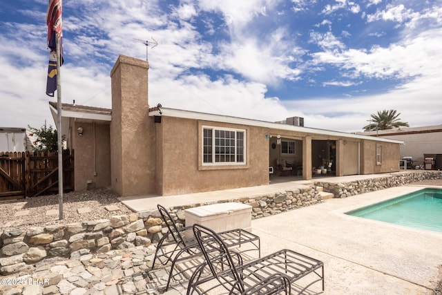 back of property with a fenced in pool, stucco siding, a chimney, a patio area, and fence