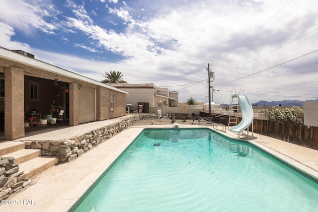 view of pool featuring a patio area, fence, a water slide, and a fenced in pool