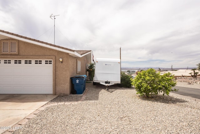 view of home's exterior with concrete driveway, an attached garage, and stucco siding