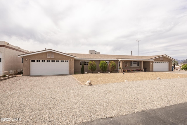 ranch-style home with a garage, stucco siding, and driveway