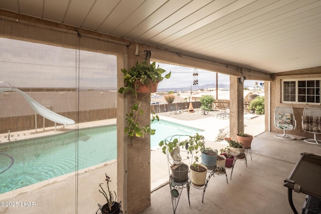view of swimming pool featuring a fenced in pool, a patio area, a fenced backyard, and a water slide