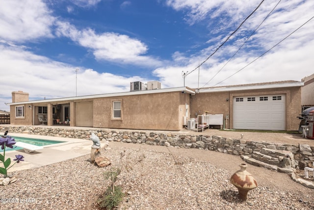 rear view of house featuring a patio area, an outdoor pool, a garage, and stucco siding