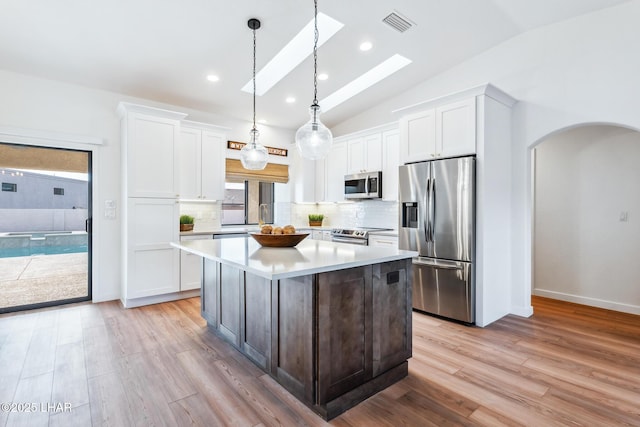 1921 Burgundy Ln, Lake Havasu City, AZ 86404 - kitchen featuring stainless steel appliances, a center island, lofted ceiling with skylight, white cabinetry, and light countertops