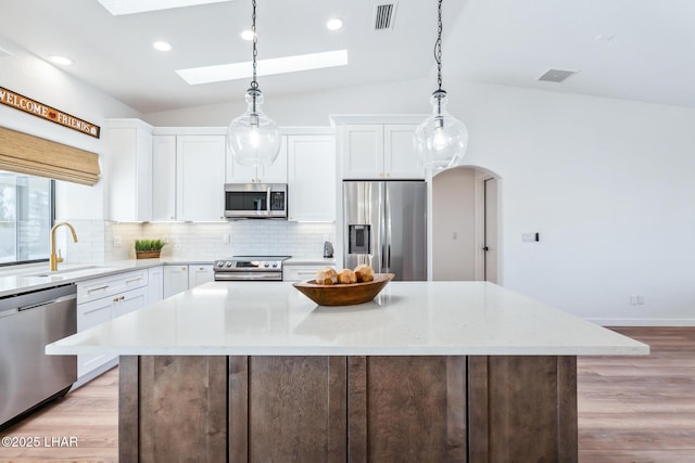 1921 Burgundy Ln, Lake Havasu City, AZ 86404 - kitchen with light wood finished floors, stainless steel appliances, a sink, lofted ceiling with skylight, and decorative backsplash