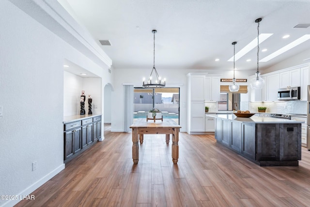 1921 Burgundy Ln, Lake Havasu City, AZ 86404 - kitchen with tasteful backsplash, light countertops, stainless steel microwave, white cabinetry, and visible vents