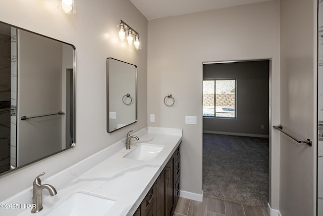 full bathroom featuring double vanity, a sink, and baseboards