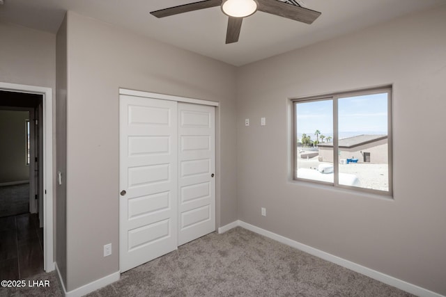 unfurnished bedroom with carpet flooring, baseboards, a ceiling fan, and a closet