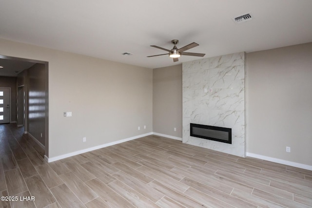 unfurnished living room featuring visible vents, wood finished floors, a ceiling fan, and a premium fireplace