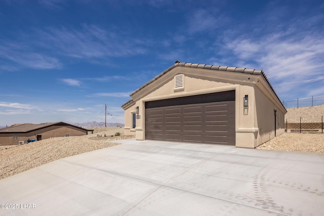 view of property exterior with an attached garage, driveway, stucco siding, and a tiled roof