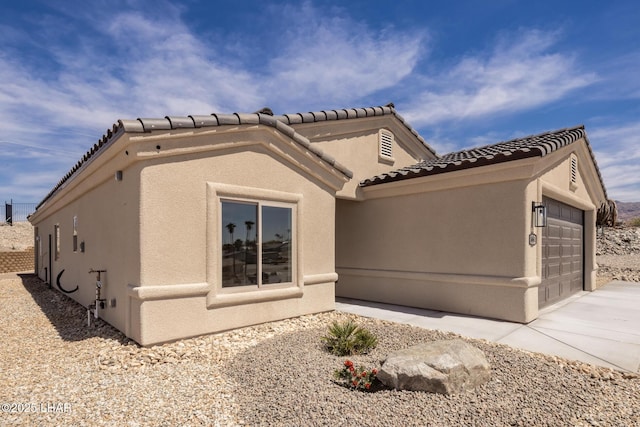view of front of house with stucco siding, concrete driveway, a tiled roof, and an attached garage