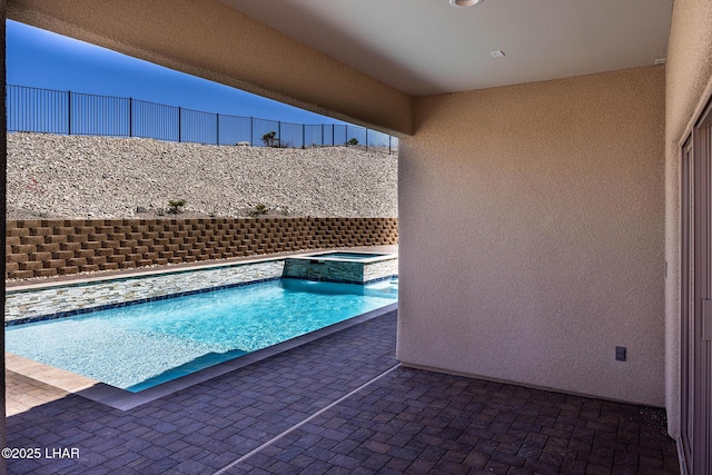 view of pool with fence and a pool with connected hot tub