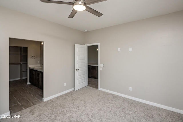unfurnished bedroom with ensuite bathroom, carpet flooring, ceiling fan, and baseboards