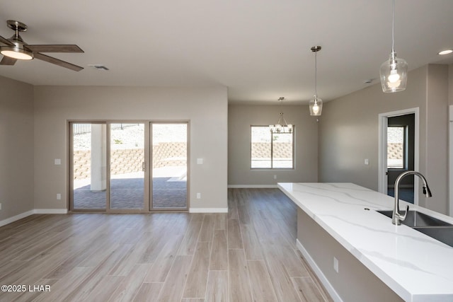 kitchen featuring a sink, light wood-style floors, visible vents, open floor plan, and ceiling fan with notable chandelier