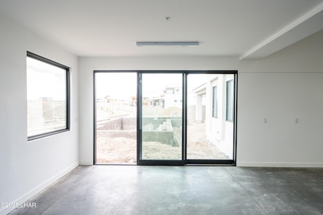 empty room featuring baseboards and finished concrete floors