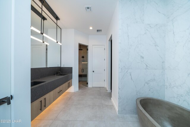 bathroom with visible vents, recessed lighting, a freestanding bath, and double vanity