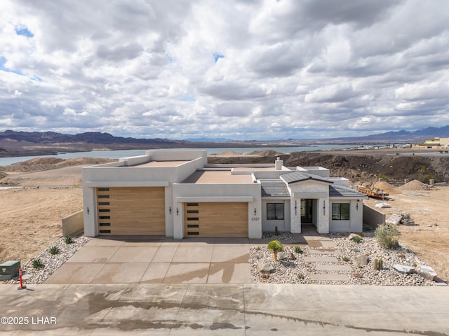 modern home with stucco siding, driveway, an attached garage, and a mountain view